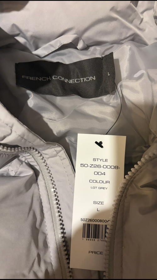 A close-up of a light gray puffer jacket showing the interior collar with a black French Connection label and a white retail hangtag attached near the zipper.